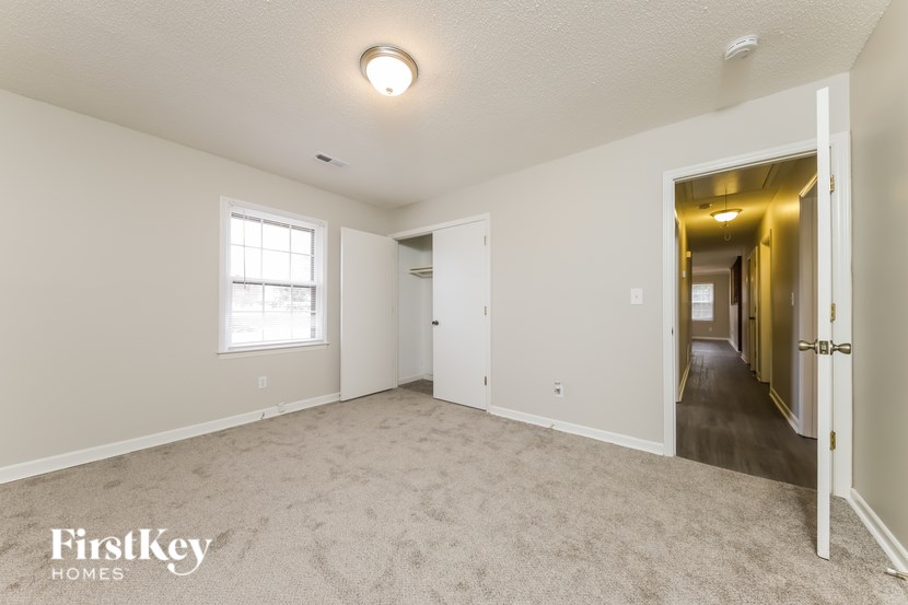 A spacious room with a carpeted floor and a window.