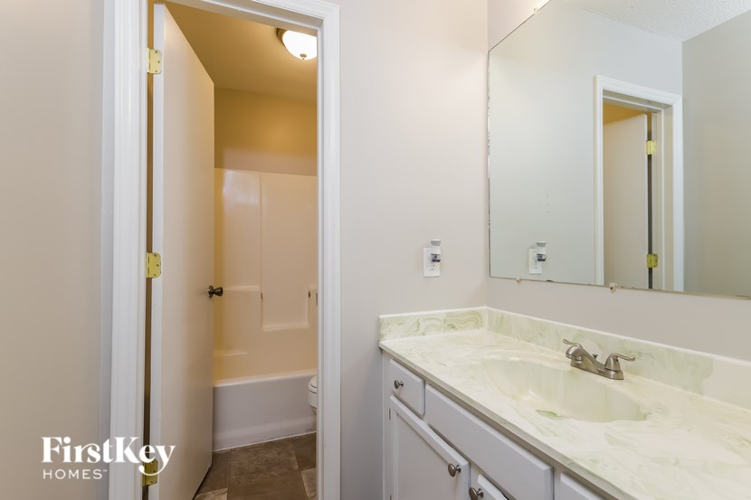 A bathroom with a sink, mirror, and a door.