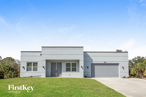 a white house with two garage doors and a lawn