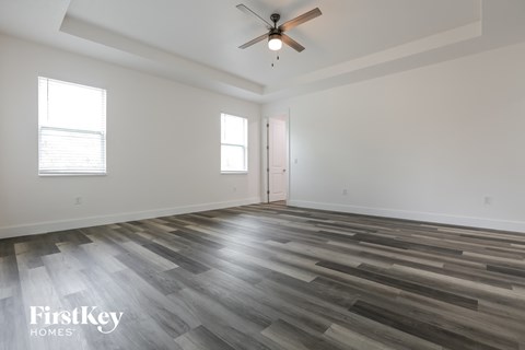 the living room of a new home with wood flooring and a ceiling fan