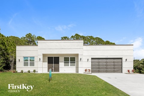 a white house with two garage doors and a lawn