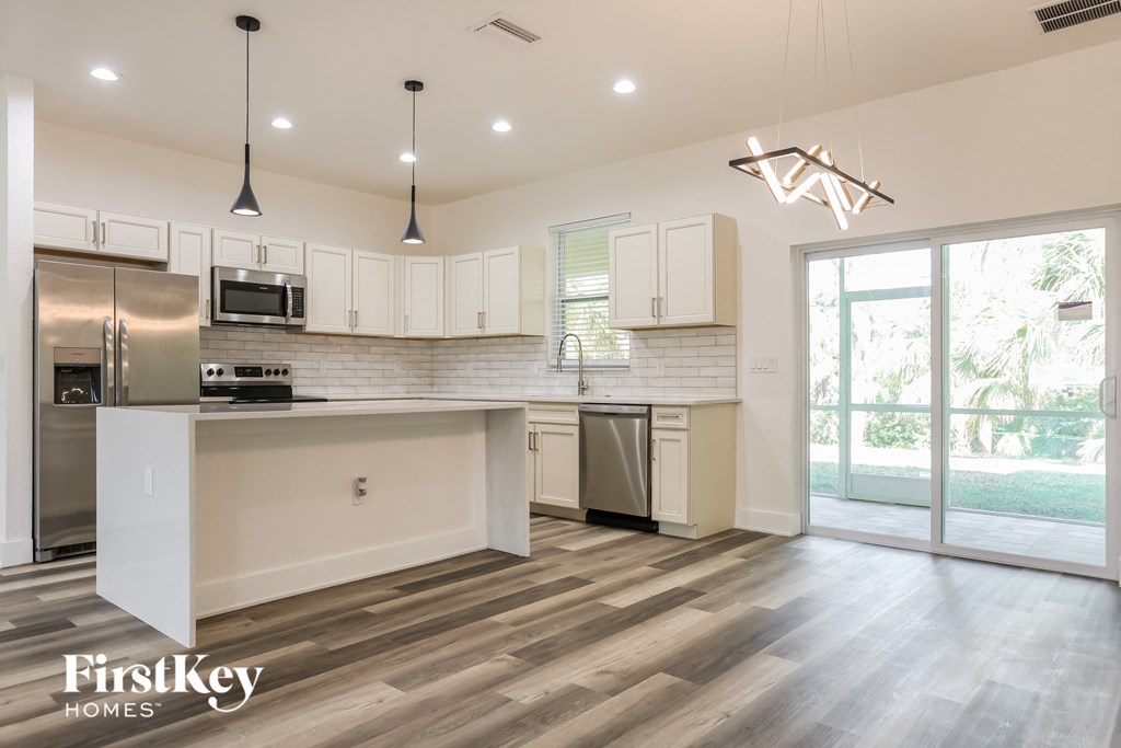 a kitchen with white cabinets and a stainless steel refrigerator