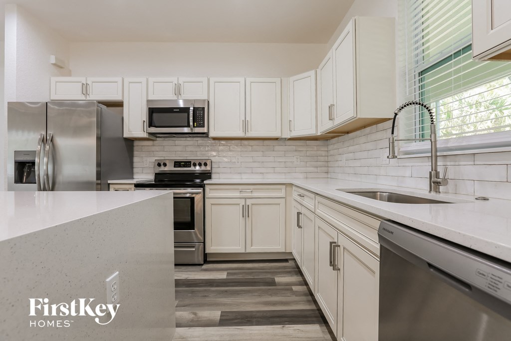 a kitchen with white cabinets and stainless steel appliances