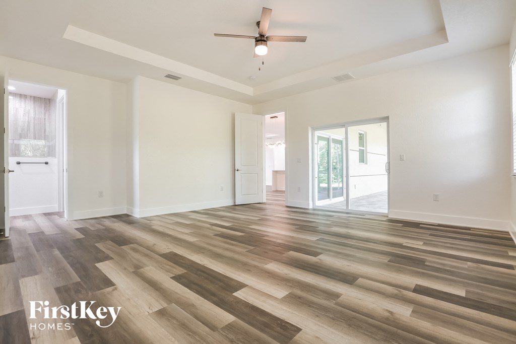 an empty living room with wood floors and a ceiling fan