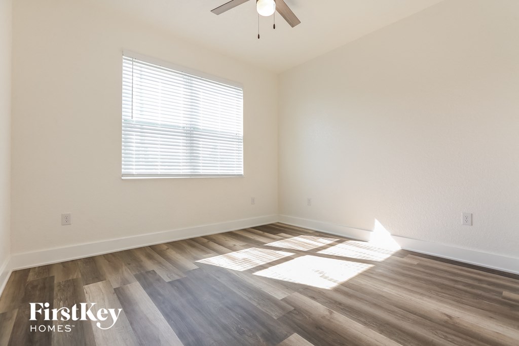 the spacious living room with wood flooring and a ceiling fan
