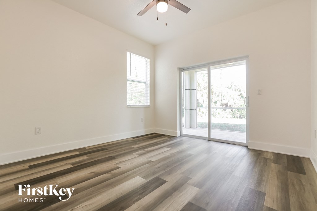 the living room of an empty house with wood flooring and a ceiling fan