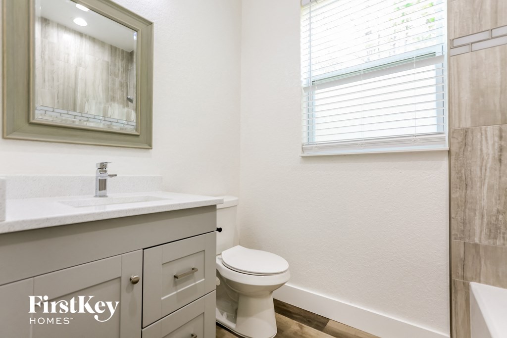 a bathroom with a toilet and a sink and a window