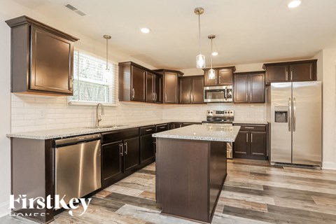 A kitchen with dark brown cabinets and a marble countertop.