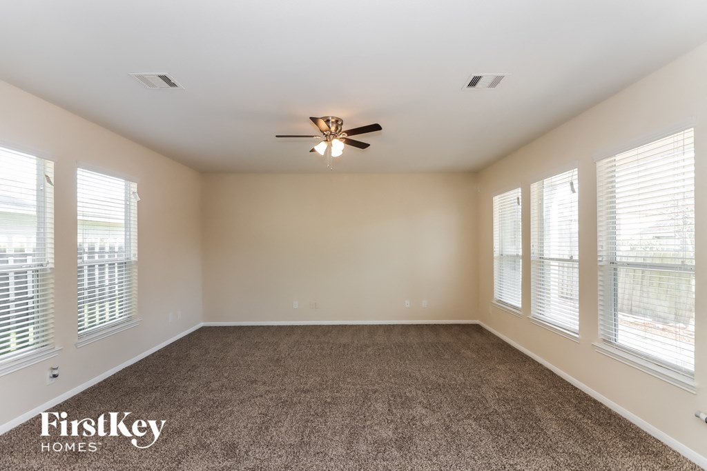 an empty living room with a ceiling fan and windows