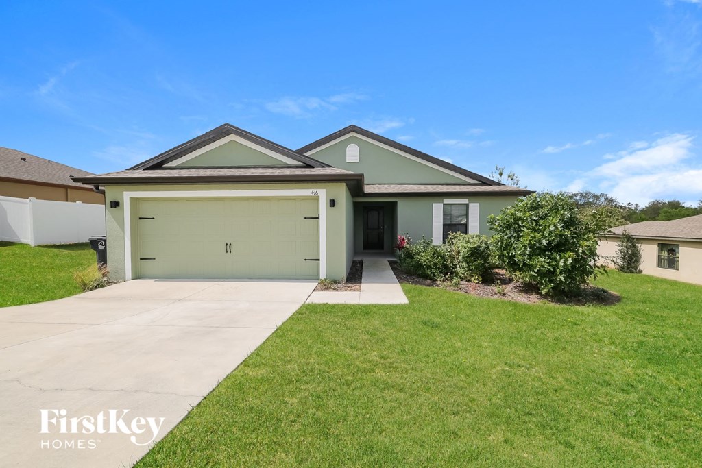 a green house with a yard and a driveway