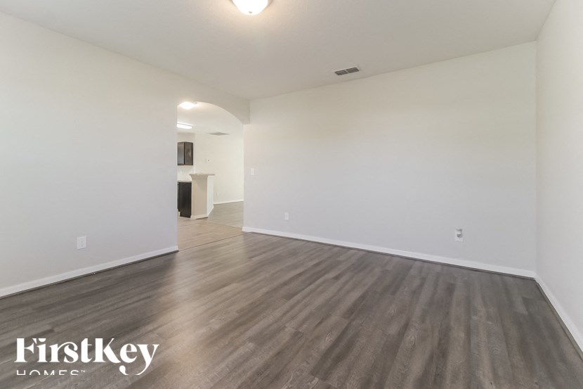 A spacious room with wooden flooring and white walls, branded with "FirstKey Homes".