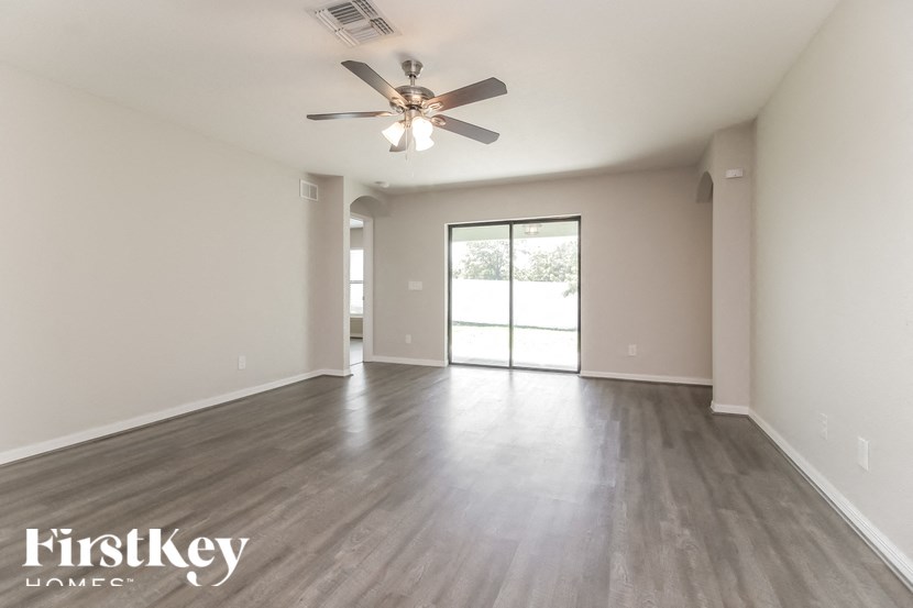 A spacious room with a ceiling fan and sliding glass doors leading to a balcony.