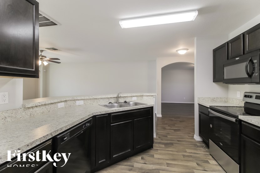 A kitchen with black cabinets and a marble countertop.