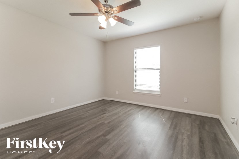 A room with a ceiling fan and a window with blinds.