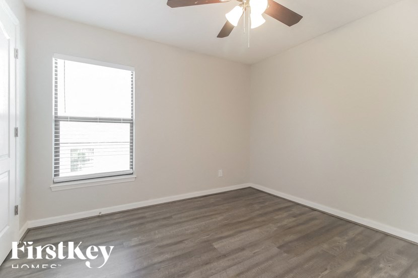 A room with a ceiling fan and a window with blinds.