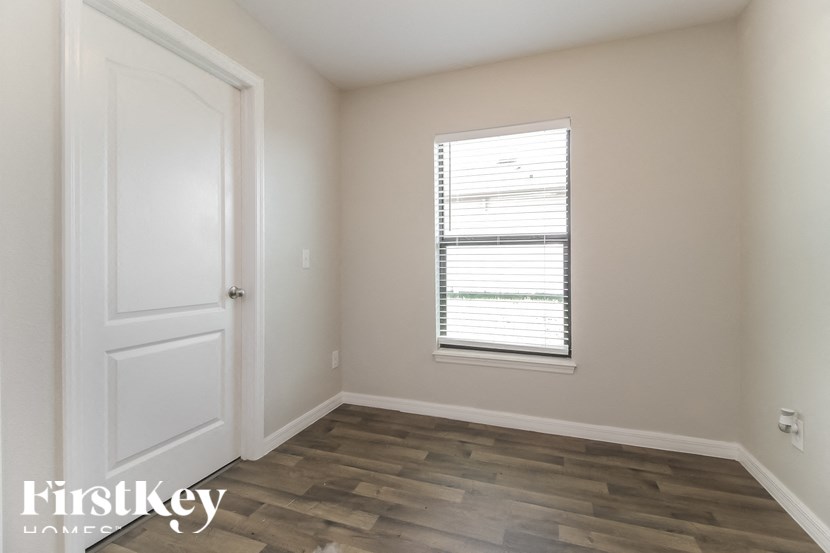 A room with a wooden floor and a window with blinds.