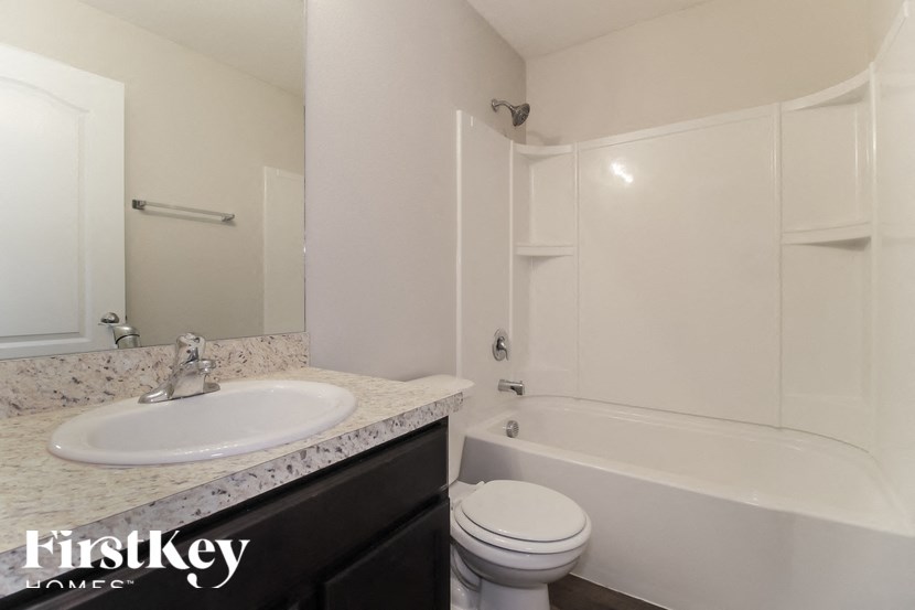 A bathroom with a white tub, sink, and toilet.