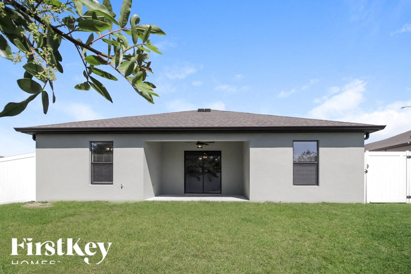 A modern house with a grey roof and a large front yard.