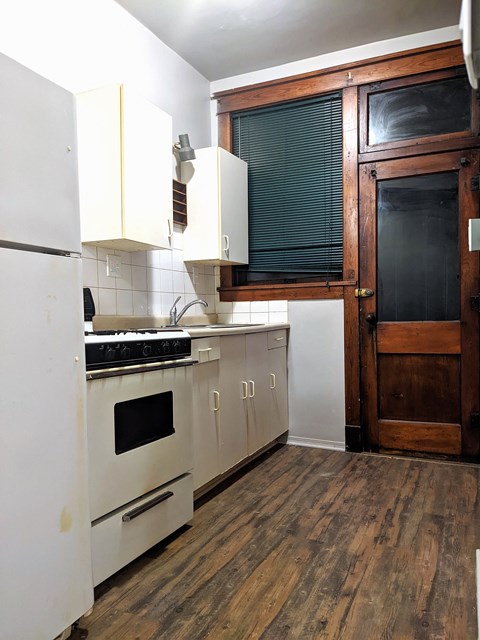 a small kitchen with white cabinets and a stove and a refrigerator
