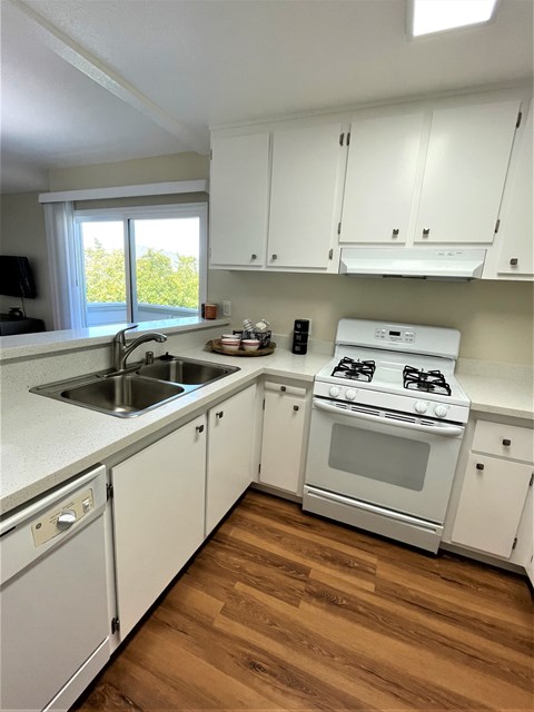 A white kitchen with wood floors and a window.