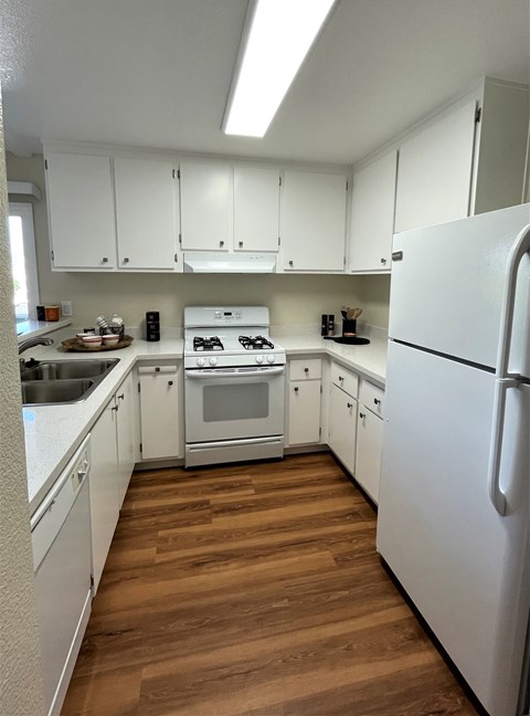 A kitchen with white cabinets and a white fridge.