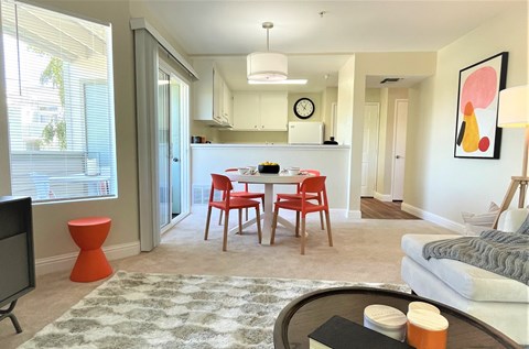 A living room with a television, a dining table with chairs, and a couch.