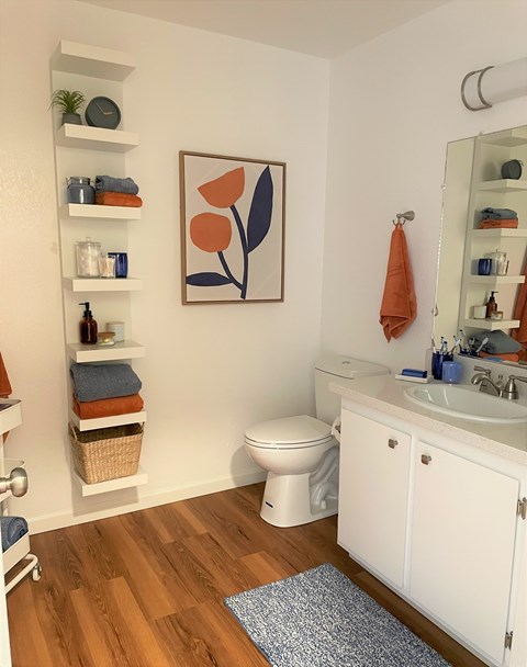 A bathroom with a toilet, sink, and a painting on the wall.