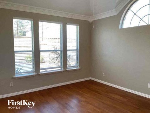 a living room with a wood floor and three windows
