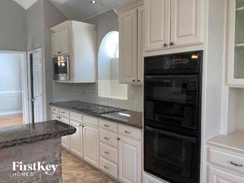 a kitchen with white cabinets and a black oven