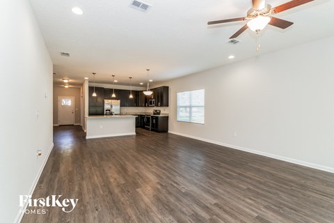 A spacious room with a ceiling fan and wooden flooring.