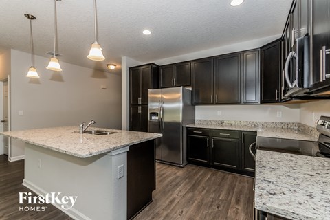 A kitchen with a granite countertop and black cabinets.