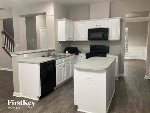 a white kitchen with white cabinets and black appliances