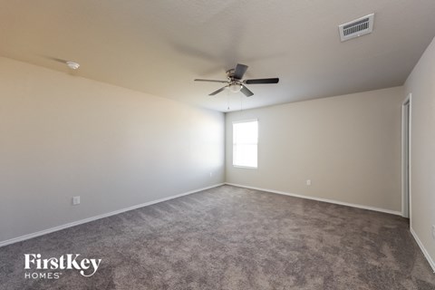 a carpeted living room with a ceiling fan