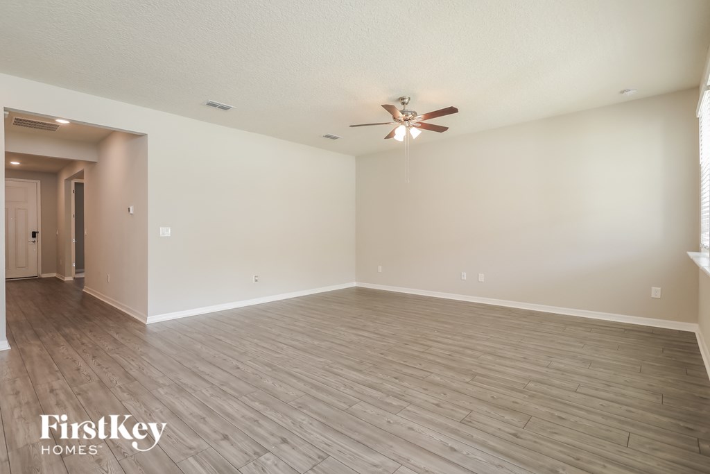 a spacious living room with hardwood floors and a ceiling fan