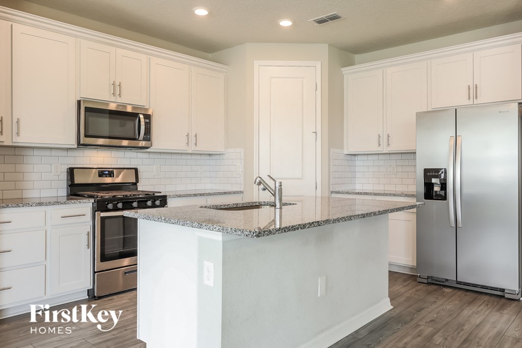 a kitchen with white cabinets and a marble counter top