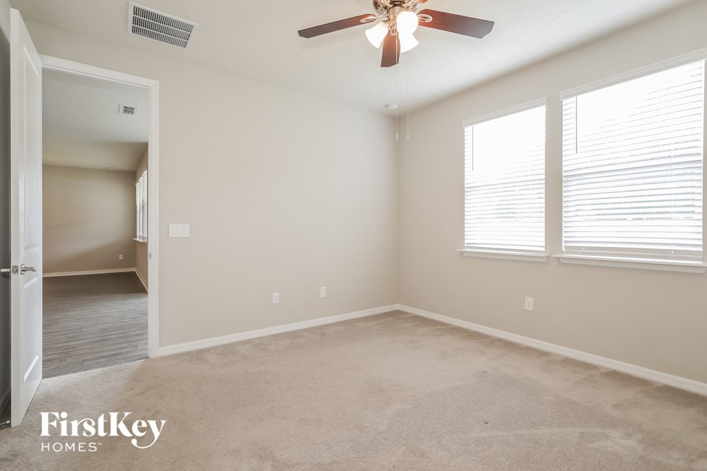an empty room with a ceiling fan and two windows