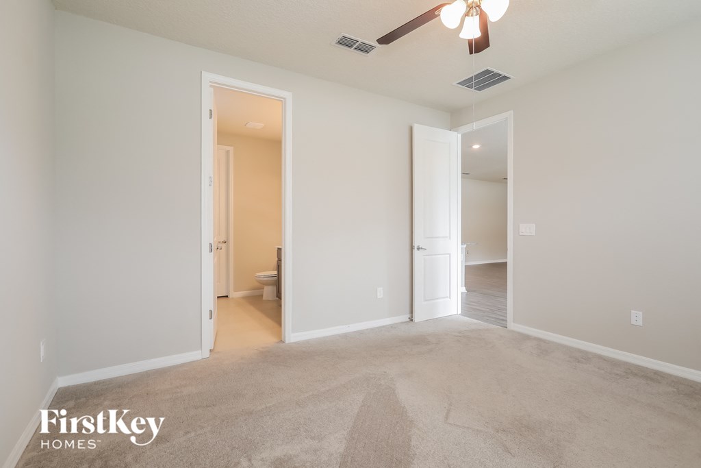 a living room with a carpeted floor and a ceiling fan
