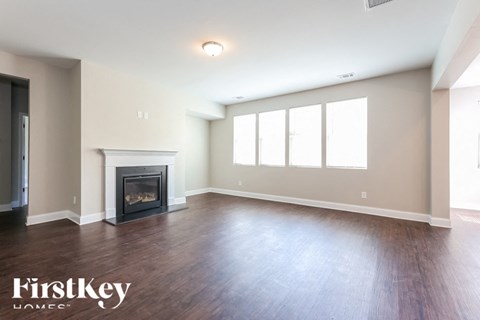 A spacious living room with a fireplace and wood flooring.