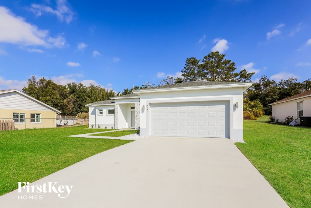a white home with a garage door and a driveway