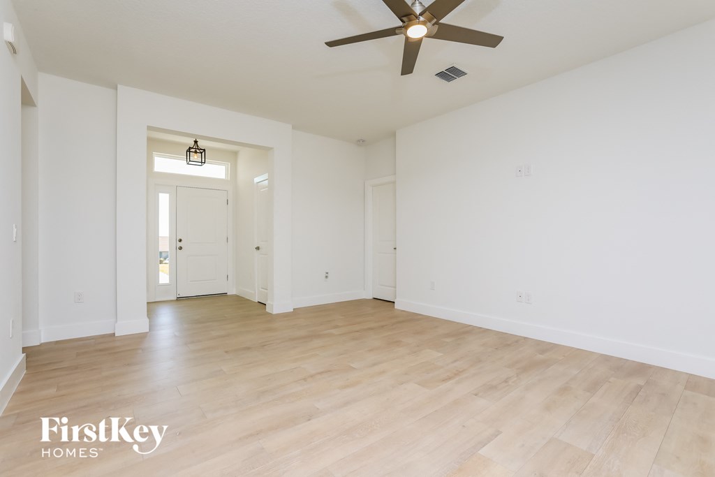 an empty living room with white walls and a ceiling fan