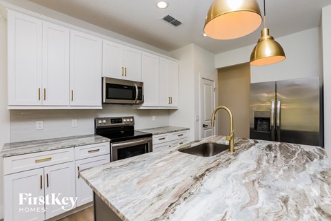 a kitchen with white cabinets and a marble counter top