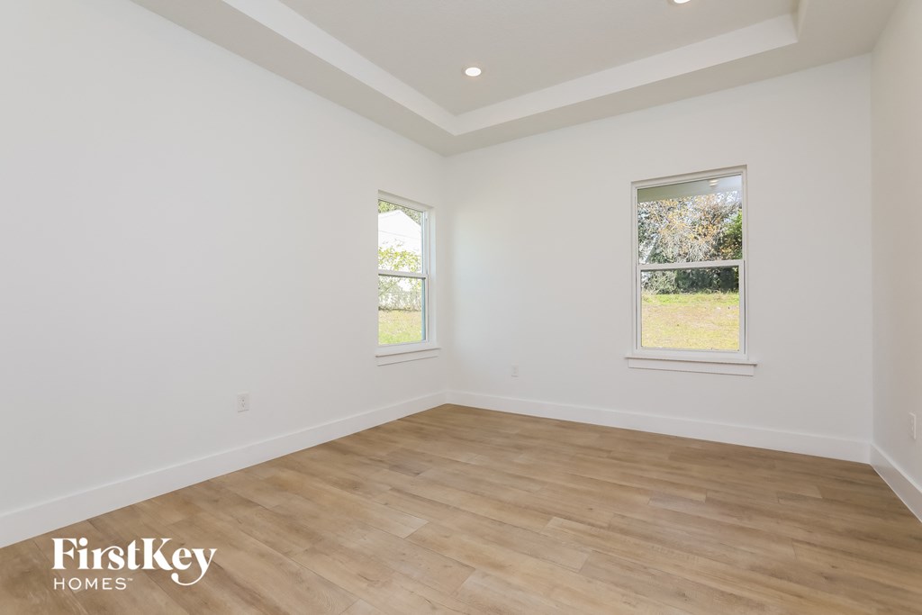 the living room of a home with white walls and wood floors