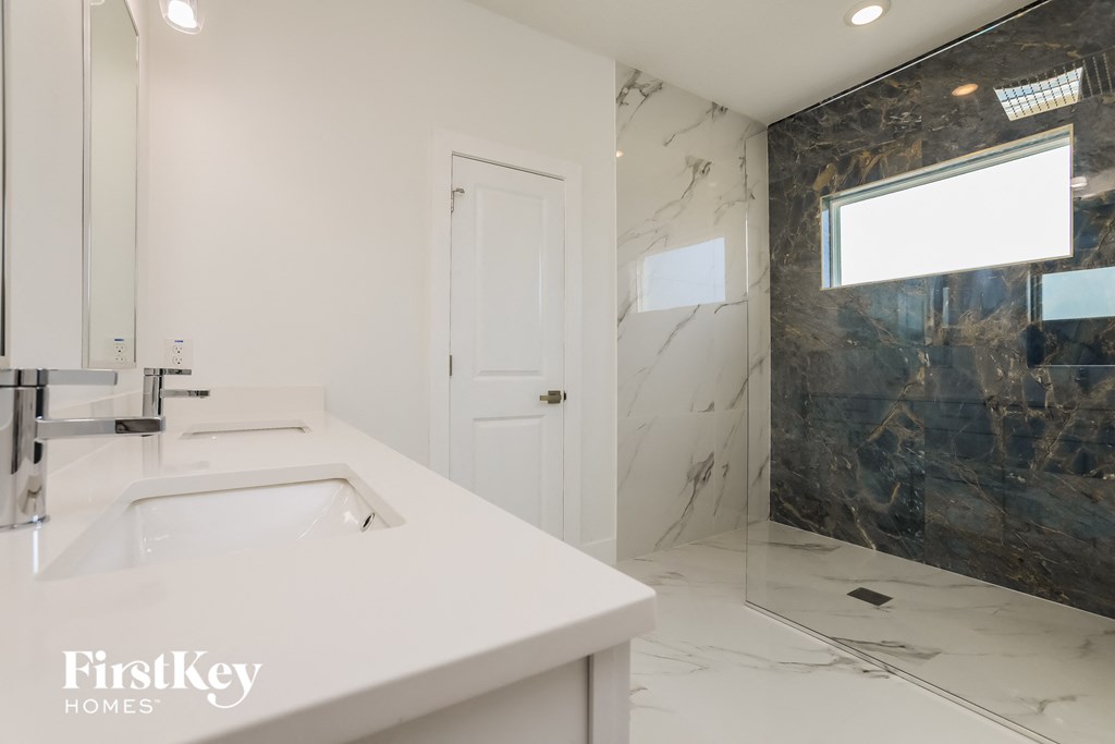 a white bathroom with a sink and a shower