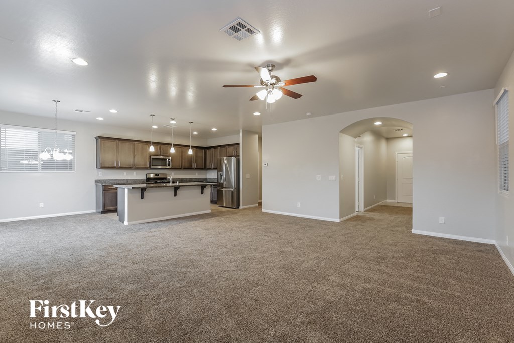 a living room with a kitchen and a ceiling fan