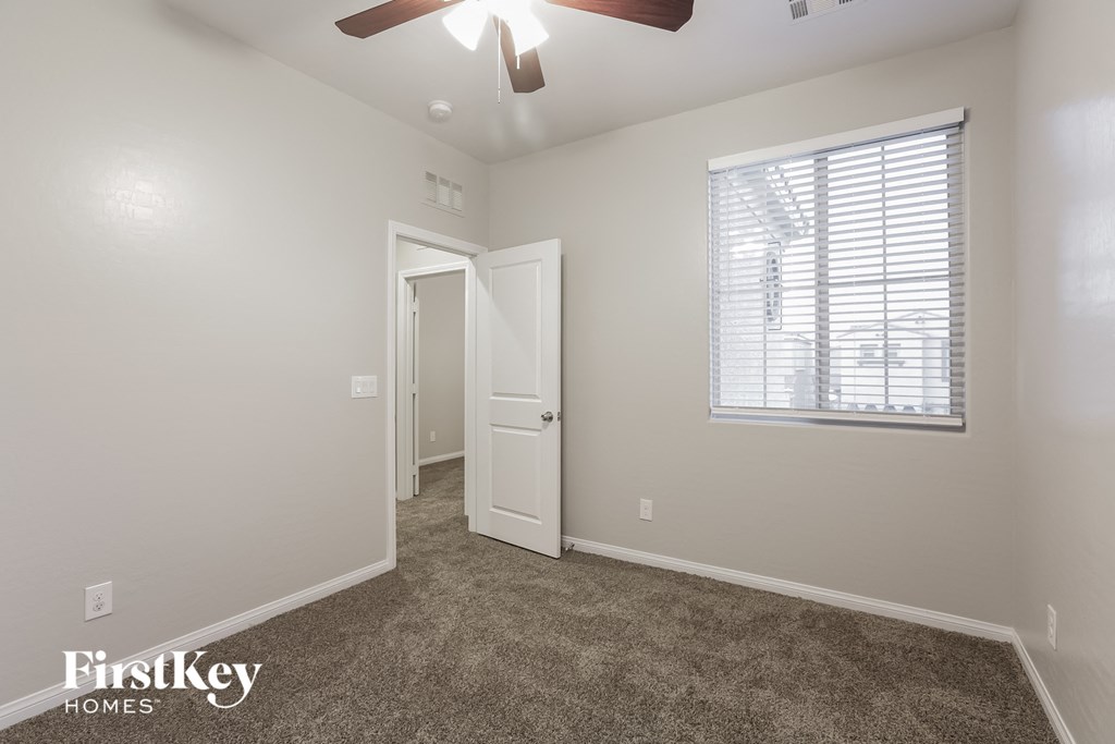 a bedroom with carpet and a ceiling fan and a window