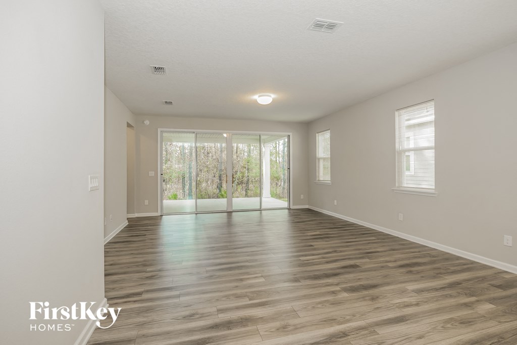 the living room and dining room of an empty house with wood flooring