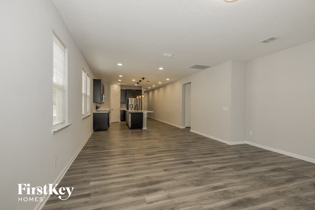 a spacious living room with white walls and wood flooring