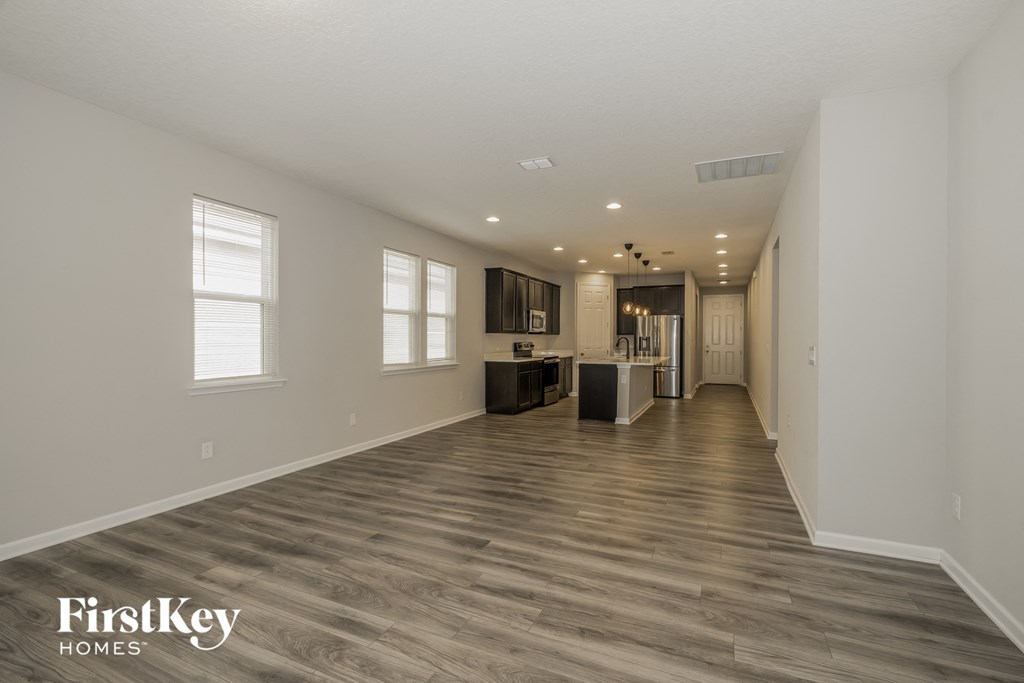 a renovated living room and kitchen with wood floors and white walls