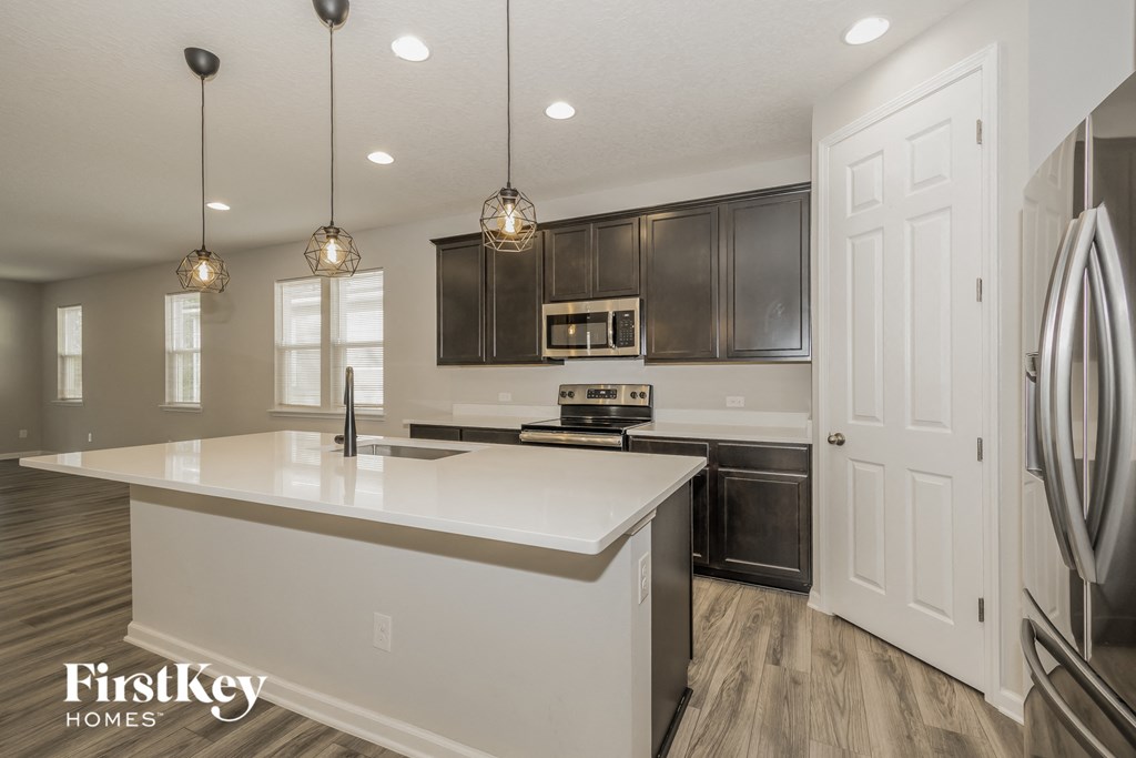 a white kitchen with black cabinets and stainless steel appliances