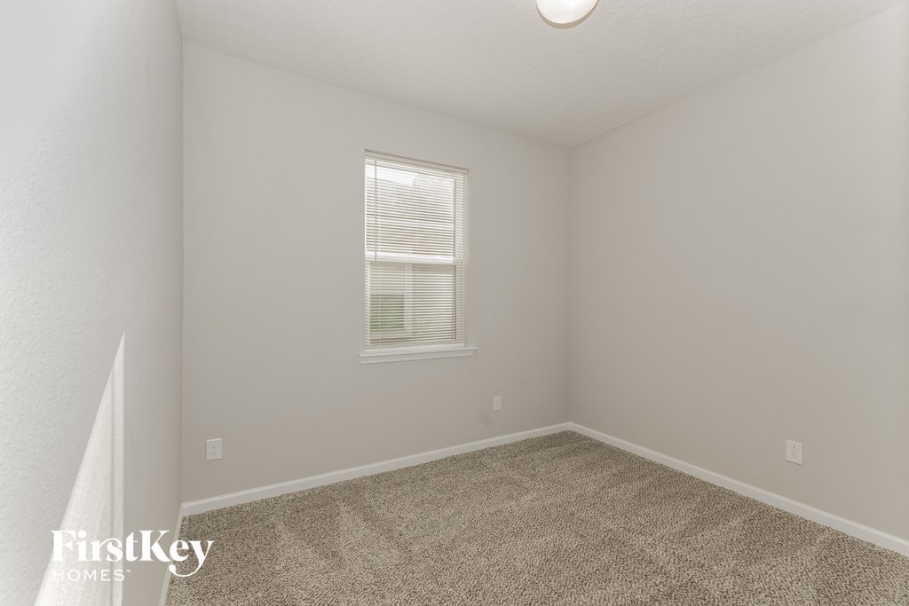 a spacious bedroom with carpeted flooring and a window